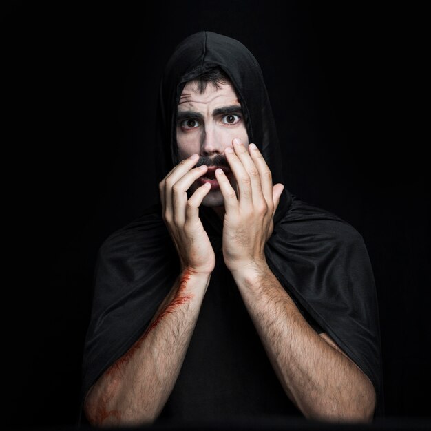 Young man in black Halloween costume posing in studio