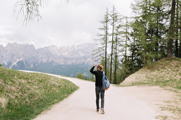 週末にイタリアの自然の景色を楽しみながら屋外で時間を過ごすバックパックを運ぶ黒いシャツを着た若い男
