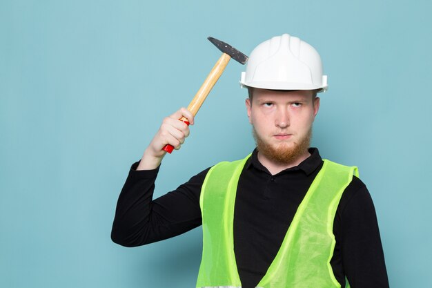 黒のシャツとハンマーを持って緑の建設ベストの若い男