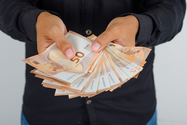 Free photo young man in black shirt holding euro banknotes