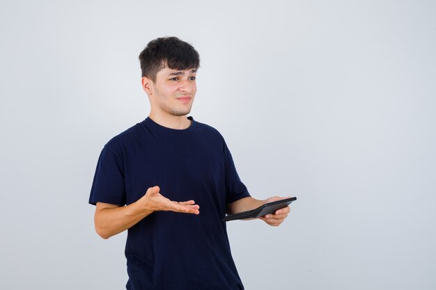 電卓を持ってがっかりしている黒いTシャツを着た若い男、正面図。