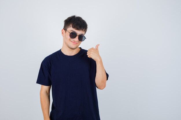 Young man in black t-shirt showing thumb up and looking confident , front view.