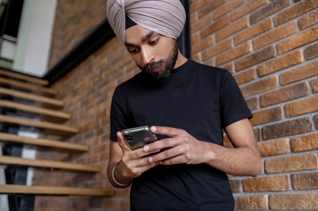 Young man in black tshirt texting on the phone and looking involved