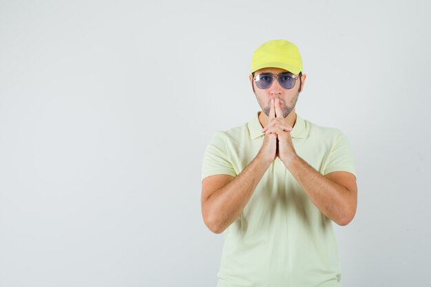 Young man blowing on finger pistol in yellow uniform and looking confident 