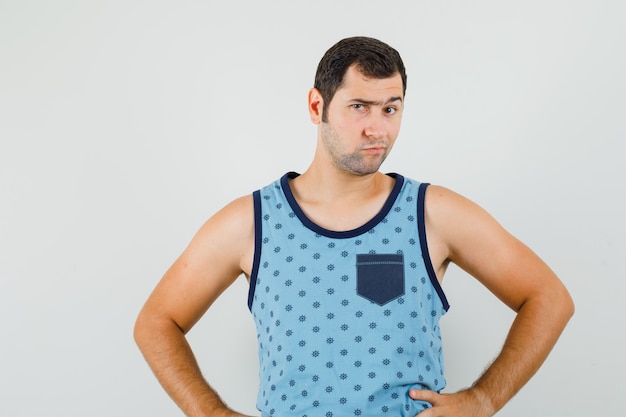 Free photo young man in blue singlet looking at camera while frowning and looking pensive