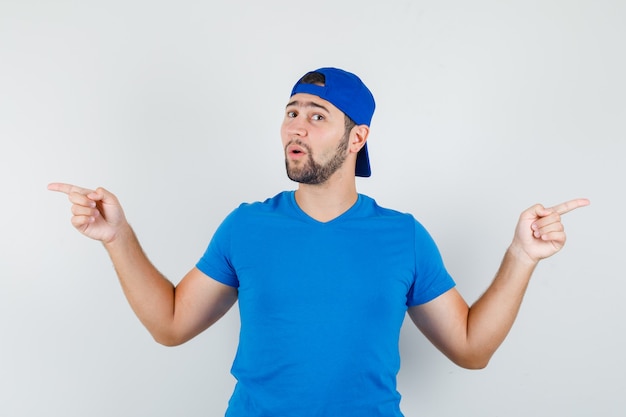 Young man in blue t-shirt and cap pointing away and looking confident