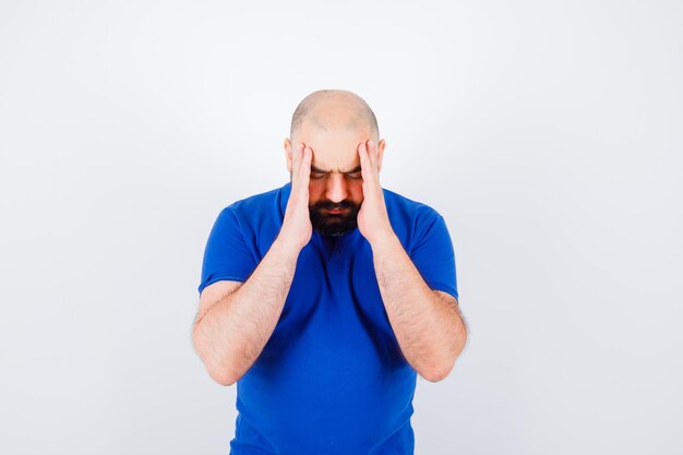 Young man in blue t-shirt having a headache