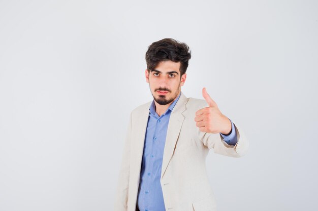 Young man in blue t-shirt and white suit jacket showing thumb up and looking serious