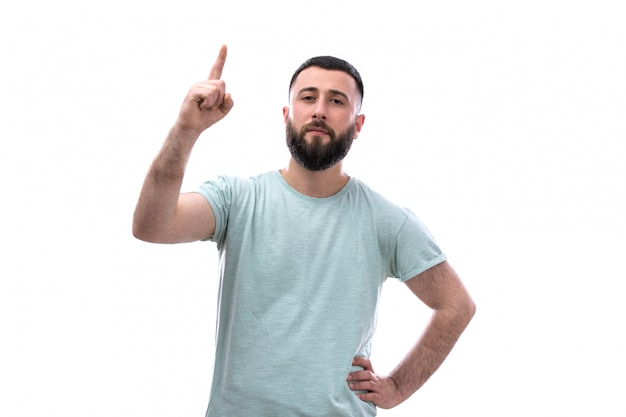 Young man in blue t-shirt with beard posing pointing his finger