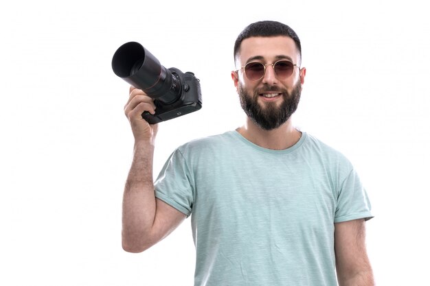 Young man in blue t-shirt with beard and sunglasses holding photo camera