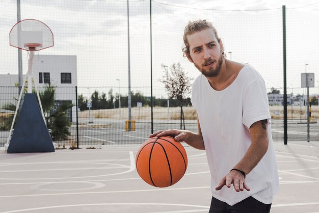 Young man bouncing basketball in court