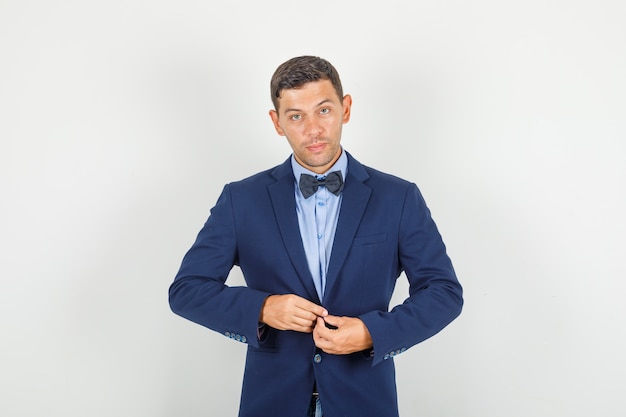 Young man buttoning his jacket in suit and looking confident.