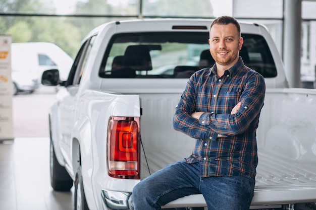 Young man buying a car in a car showroom