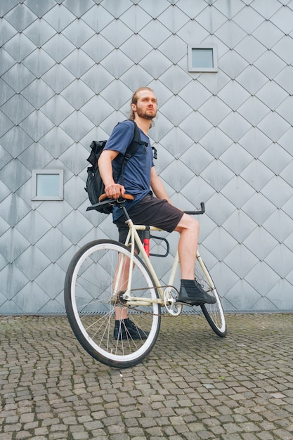 Young man carrying backpack riding bicycle at outdoors