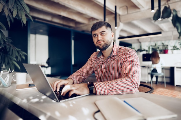 Young man in casual shirt working on computer in office