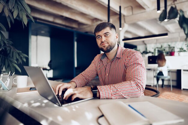 Молодой человек в повседневной рубашке, работая на компьютере в офисе