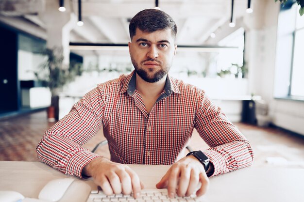 Young man in casual shirt working on computer in office