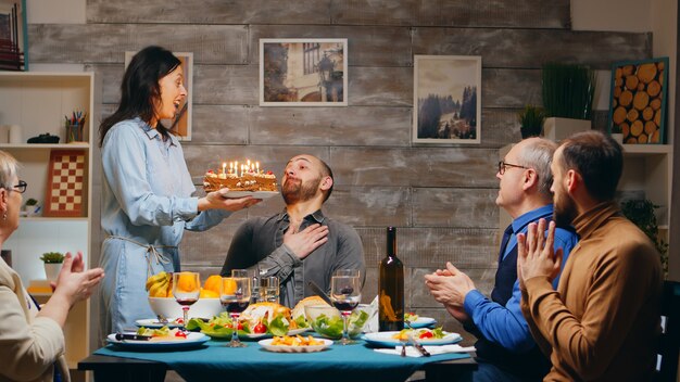 Young man celebrating his birthday with the family. Dinner food. Delicious cake. Slow motion shot