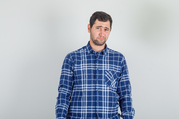 Young man in checked shirt frowning face as going to cry and looking upset