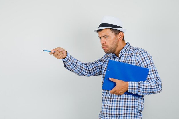 Young man in checked shirt, hat holding clipboard