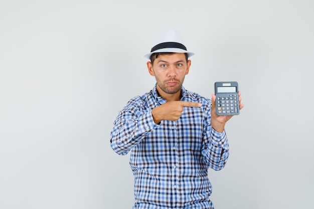 Молодой человек в клетчатой рубашке, шляпе, указывающей на калькулятор и серьезно выглядящей