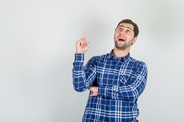 young man in checked shirt pointing finger up and looking happy