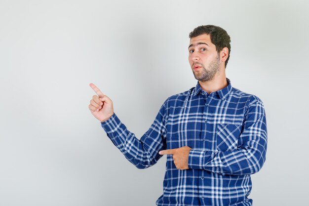 Young man in checked shirt showing something with fingers