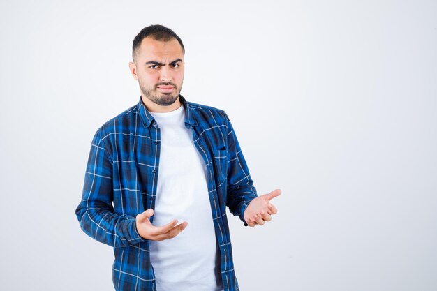 チェックシャツと白いTシャツを着た若い男が何かを受け取ってイライラしているように手を伸ばしています