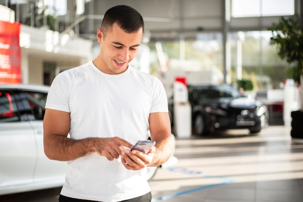 Young man checking his phone at dealership