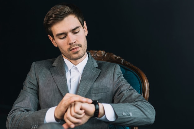 Young man checking time on his watch against black background