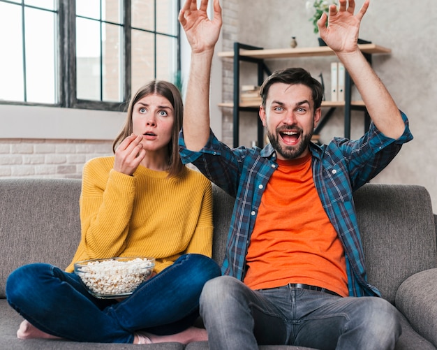 Young man cheering while watching the match television sitting with his wife