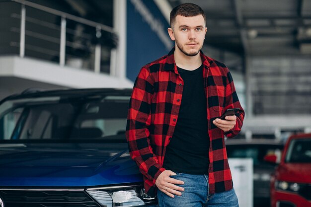 若い男が車のショールームで車を選ぶ