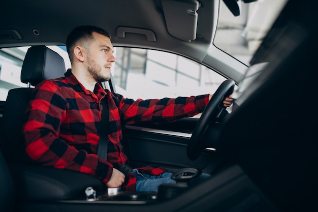 Young man choosing a car in a car showroom