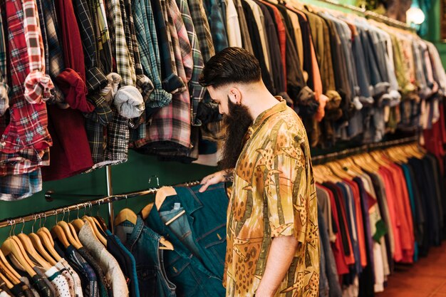 若い男がショールームのラックに服を選ぶ