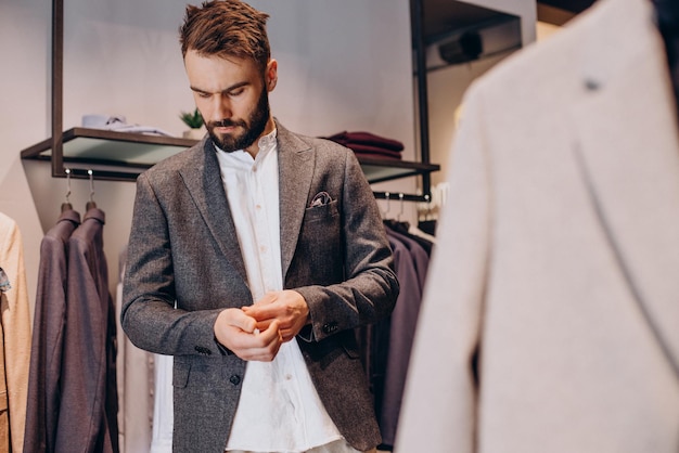 Young man choosing cloths in menswear shop Free Photo