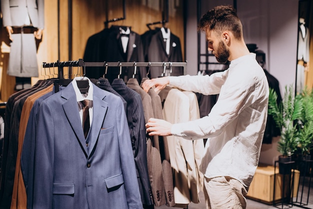 Free photo young man choosing cloths in menswear shop