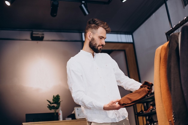 Young man choosing cloths in menswear shop