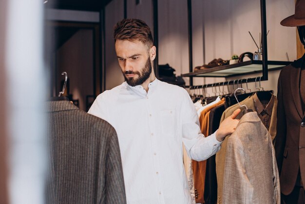 Young man choosing cloths in menswear shop