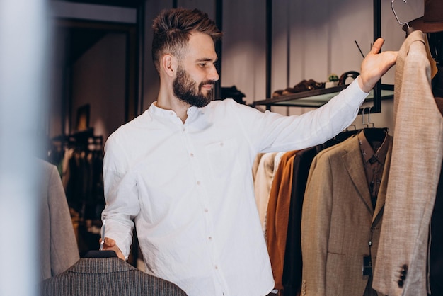 Free photo young man choosing cloths in menswear shop