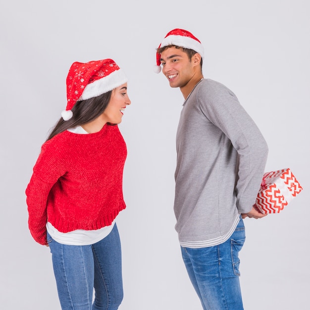 Giovane in cappello di Natale con scatola presente vicino donna attraente