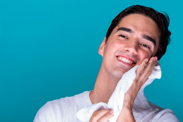 Free photo young man cleansing face with towel