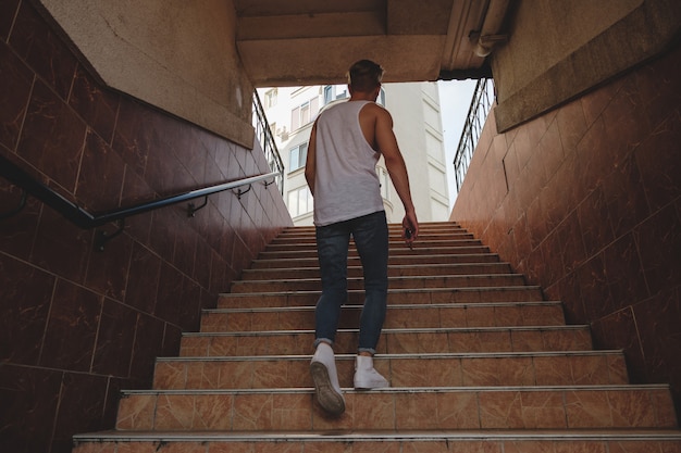 Молодой человек поднимается по лестнице в пешеходном метро