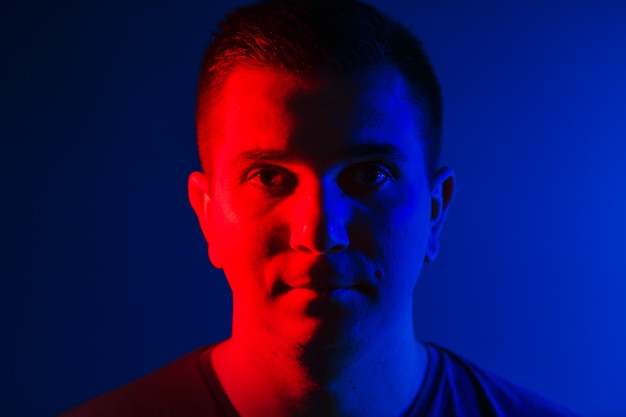 Free photo young man close head portrait red blue double colors light