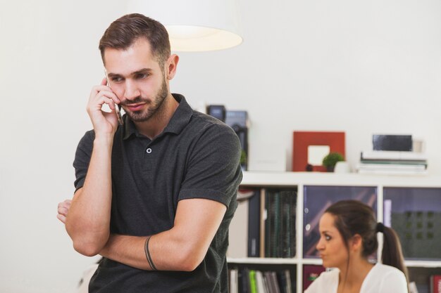 Young man conversating with phone in office