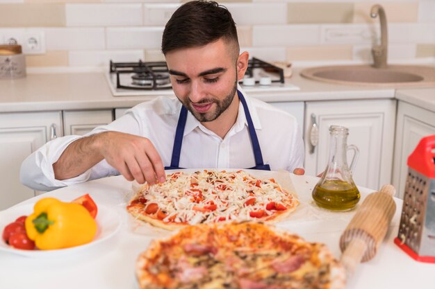 Young man cooking pizza in kitchen 