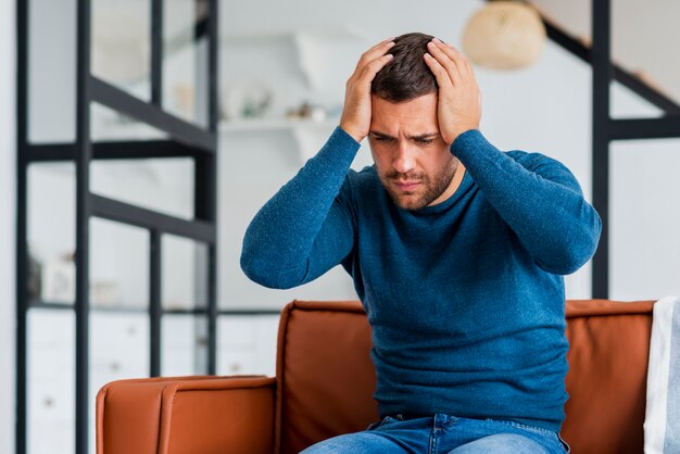 Young man on couch holding hands at head