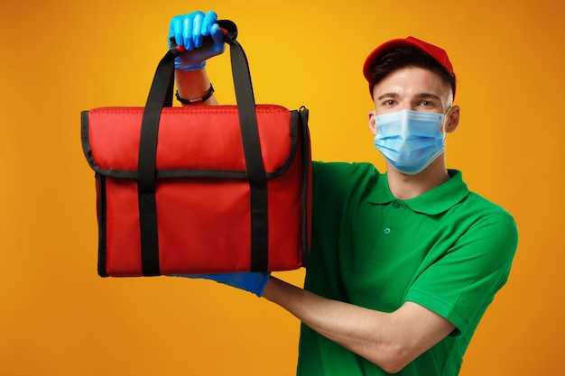 Young man courier in face mask with thermo bag