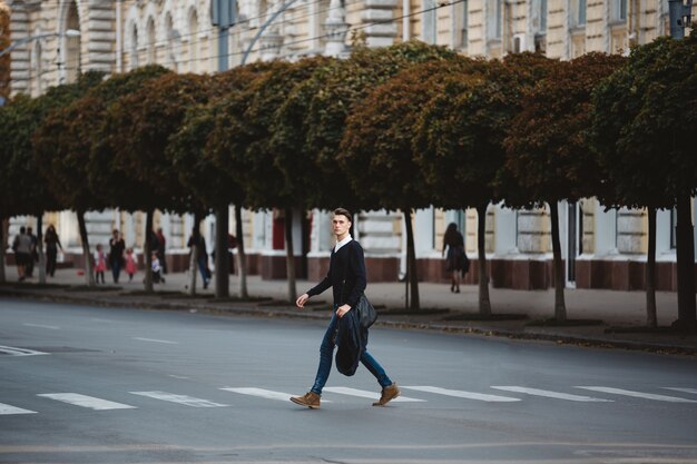 Молодой человек переходит улицу