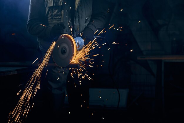 Young man cutting with rotating disc for metal with sparks