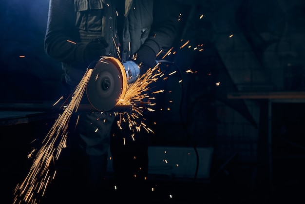 Young man cutting with rotating disc for metal with sparks